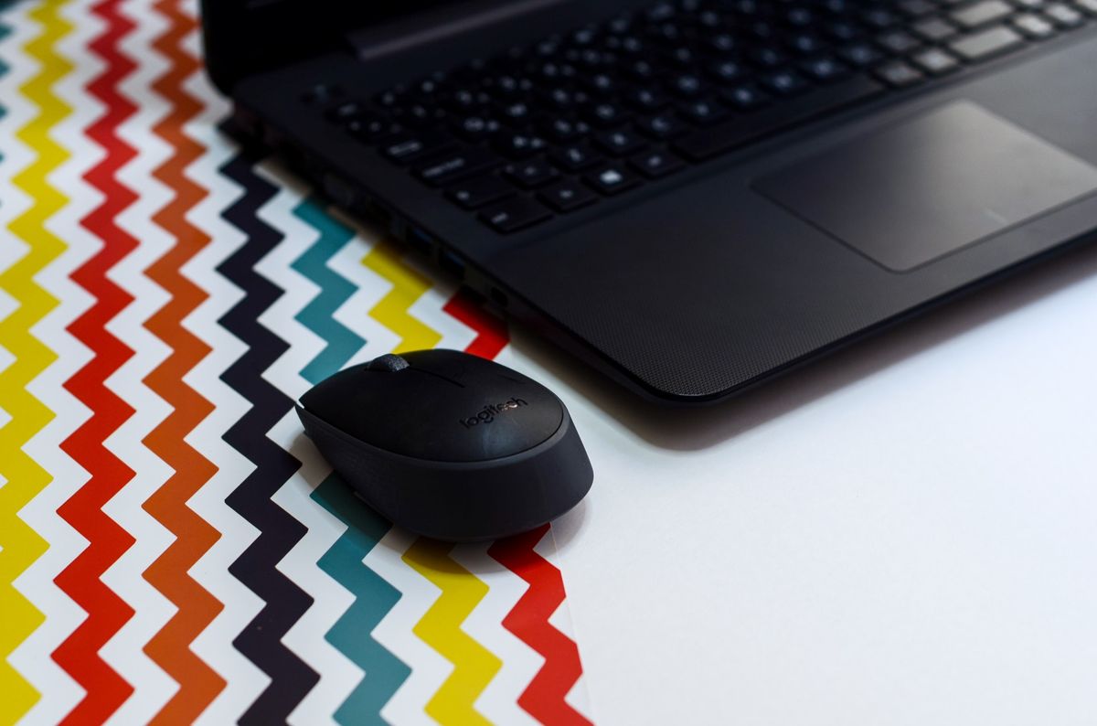 Laptop mit Maus auf einer bunt gemusterten Unterlage